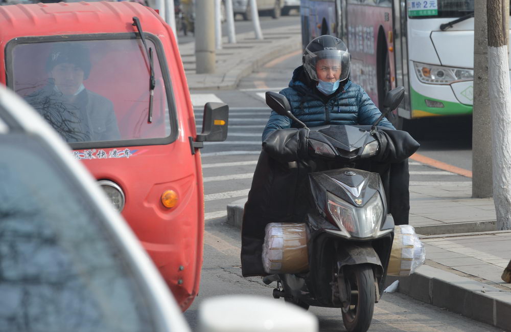 沈阳迎来黄尘大风天气 街头市民顶风骑行